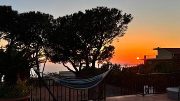 A hammock on a patio with a sunset view.