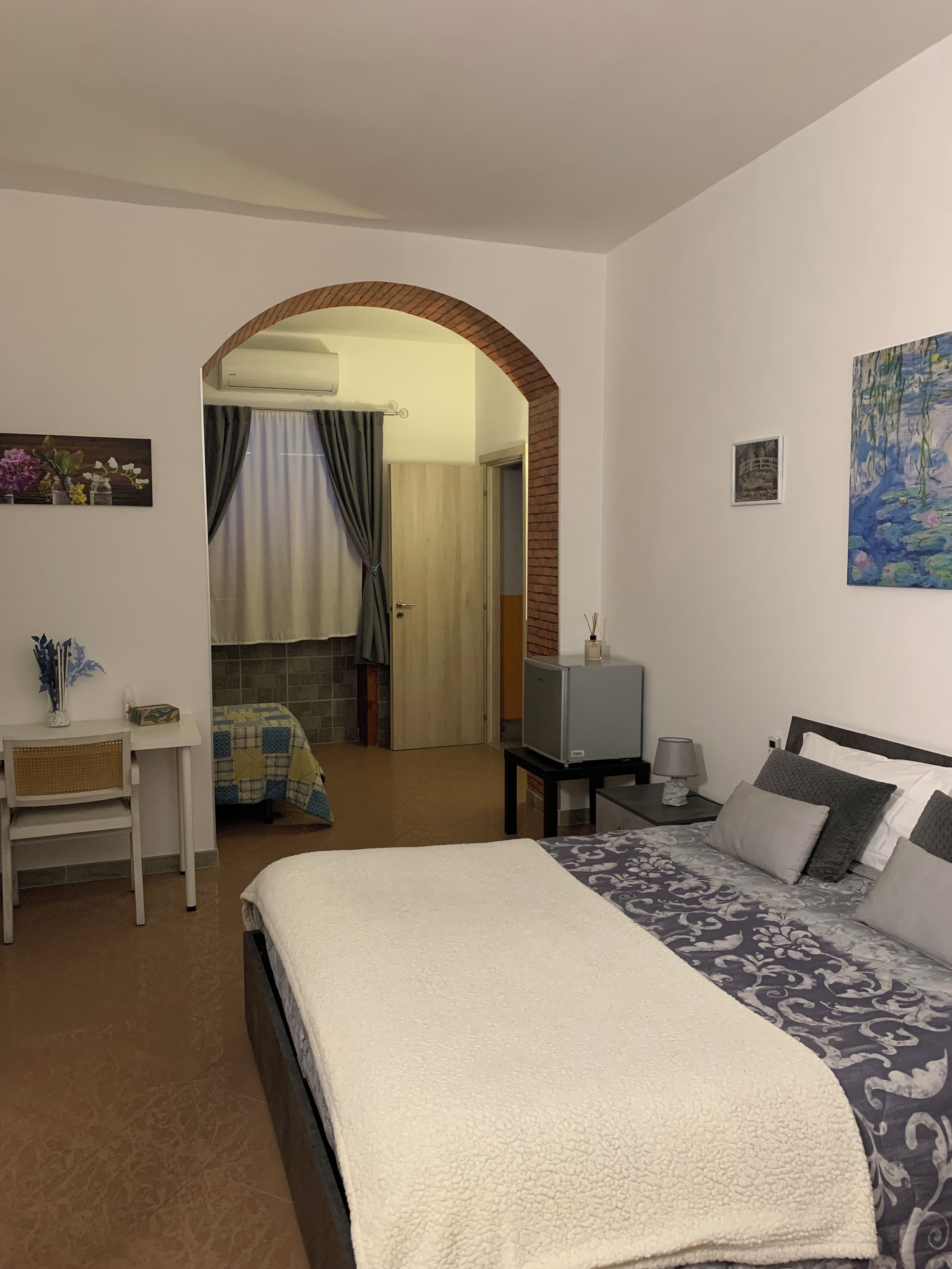 Un dormitorio con cama, escritorio, televisor y un cuadro en la pared.