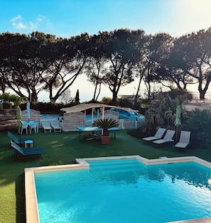 A backyard with a swimming pool, lounge chairs, and a patio area.