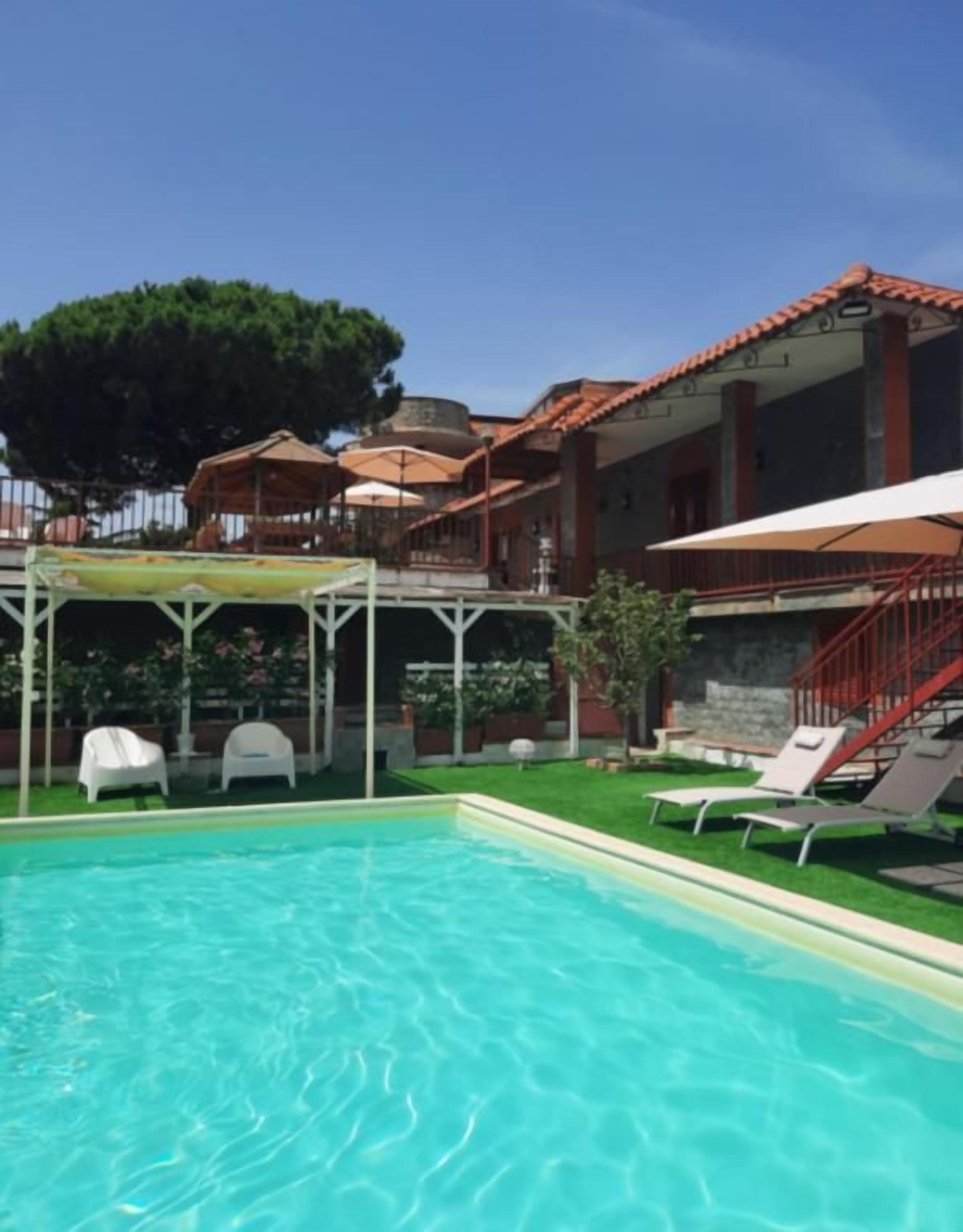 Une piscine avec des chaises longues et un espace abrité équipé de parasols.