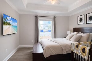 Une chambre d’hôtel avec un lit, une télévision, une fenêtre avec des rideaux et une vue sur la plage.