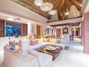 A spacious living area with a high ceiling, a large sofa set, a coffee table, and a painting on the wall. - Casa Cantarena—Private Beach, 4 Bedrooms, 4 Bathrooms, Chef + Concierge (Quintana Roo)