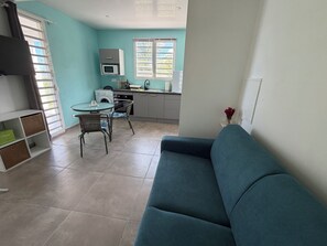 Un espace de vie compact comprenant une kitchenette, un coin repas et un canapé.