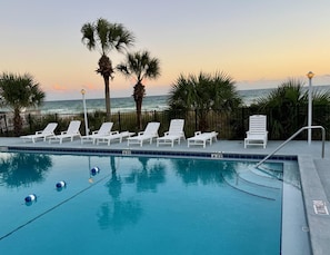 A poolside area with white lounge chairs and palm trees, overlooking the ocean. - The Shores Townhome #111 - Saltwater Sunset (Panama City Beach)