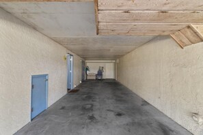 A narrow hallway with a blue door on the left, a white door at the end, and a chair in the center. - The Shores Townhome #111 - Saltwater Sunset (Panama City Beach)