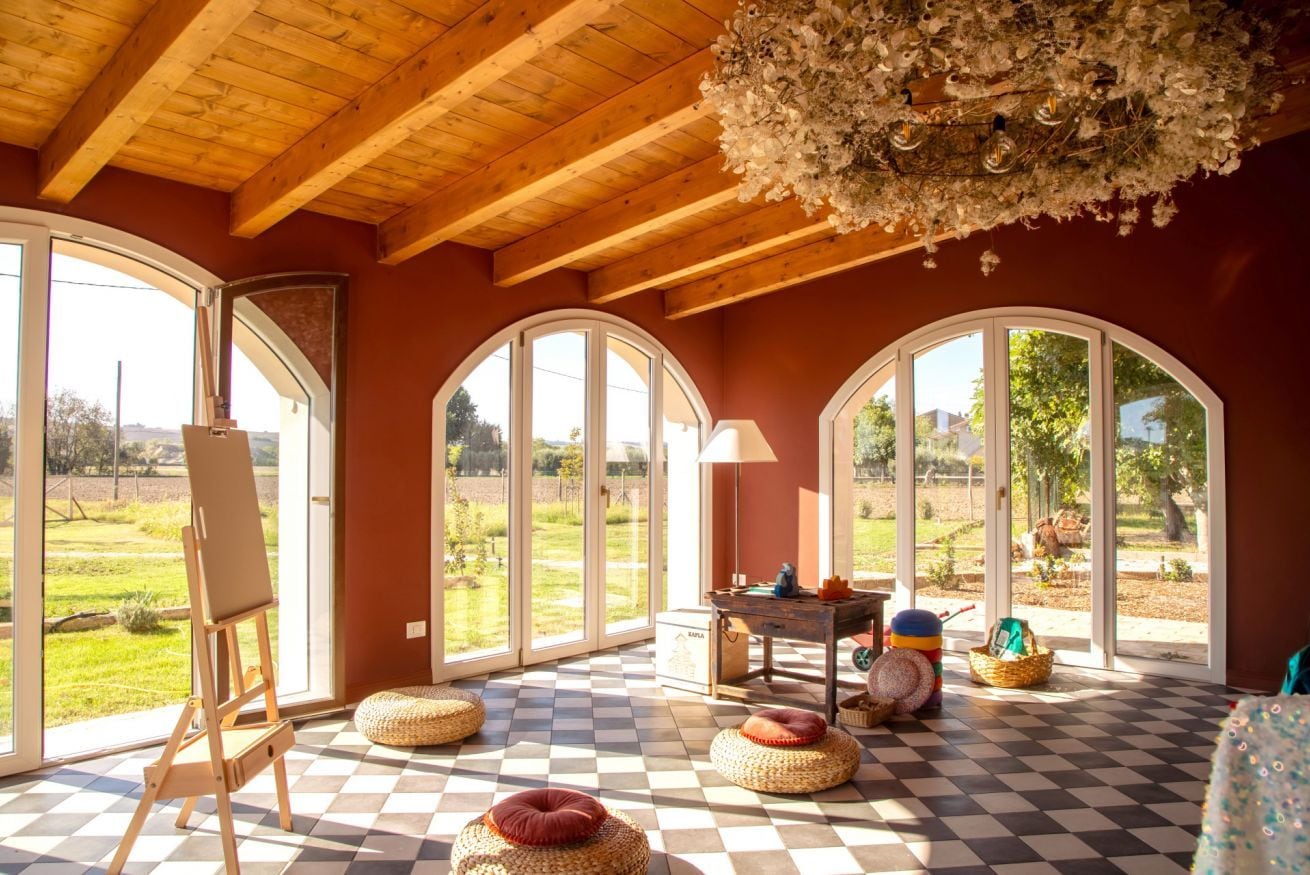 A room with large arched windows, a wooden ceiling, and a checkered floor.
