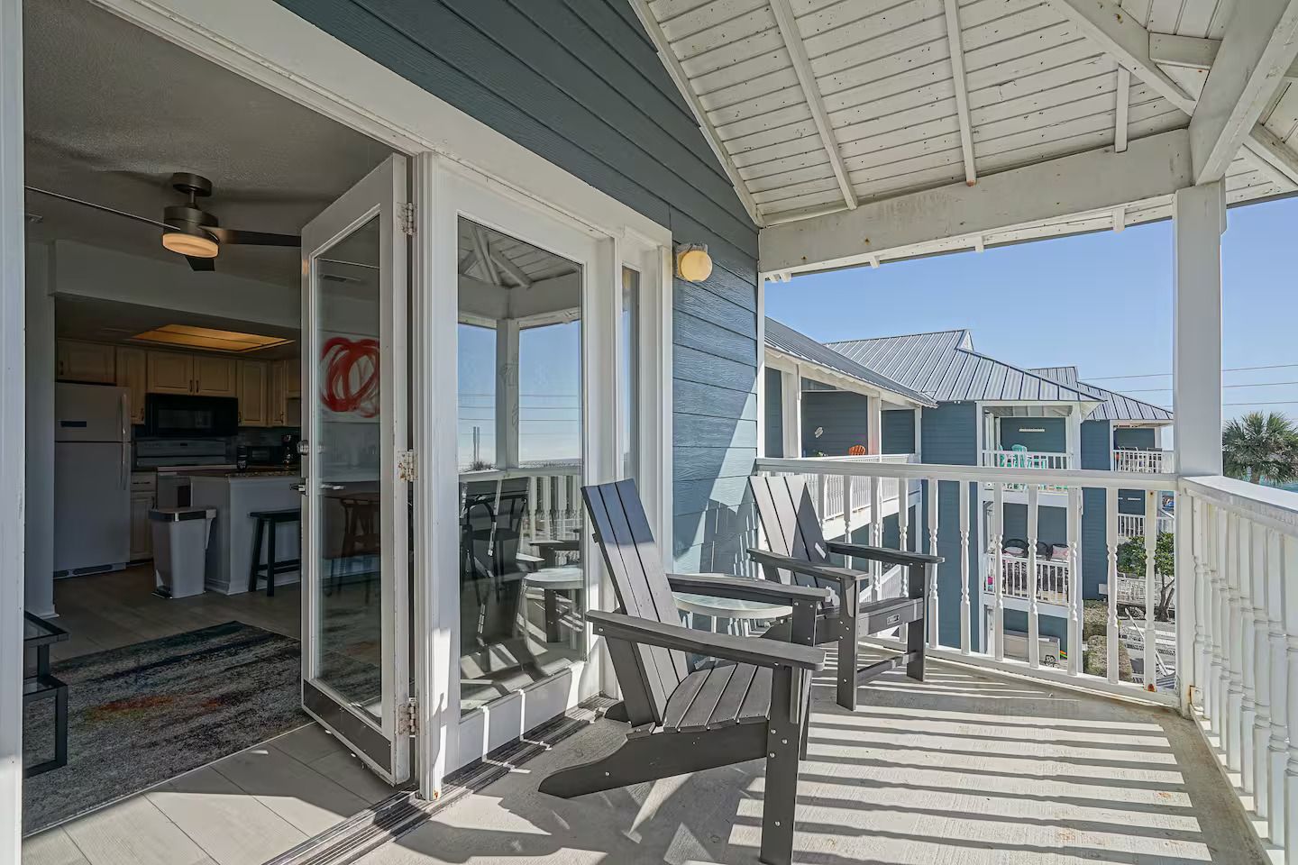 A covered porch with outdoor seating and a view of a residential area.