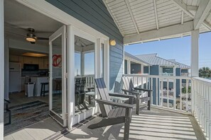 A covered porch with outdoor seating and a view of a residential area. - ⭐Across St from Beach Access-Gulf Views-Pool+Hot Tub-Summer Breeze 310⭐ (Miramar Beach)