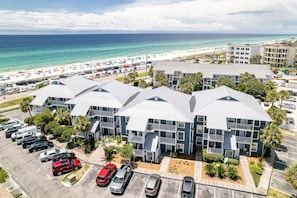 Ett hotell vid stranden med flera byggnader, en parkeringsplats och en strand i bakgrunden.