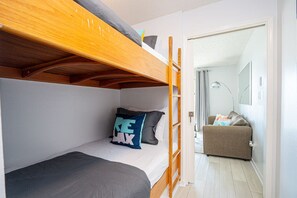 Ett litet rum med en våningssäng, en liten soffa och en dörr som leder till ett annat rum.