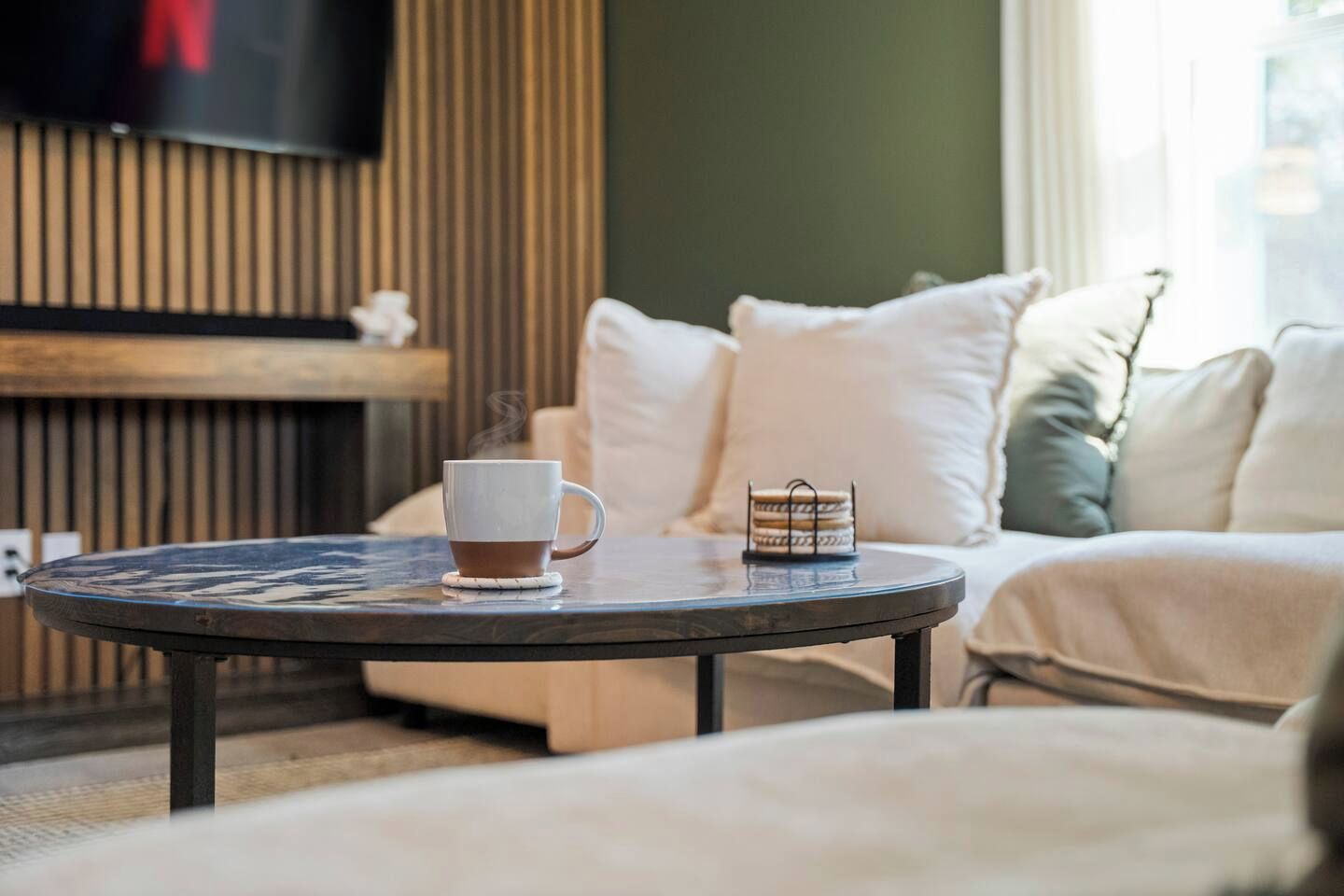 Un salon chaleureux avec une table basse ronde, une tasse blanche et un petit panier.