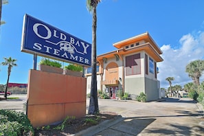A sign for Old Bay Steamer, a building with a red door, and a parking lot with palm trees. - 🎣 Palm Court Yacht Club 312A | Waterfront Views, Pool & Fishing Dock 🌊 (Fort Walton Beach)