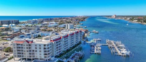 A coastal hotel with multiple floors, a marina with boats, and a clear view of the ocean.