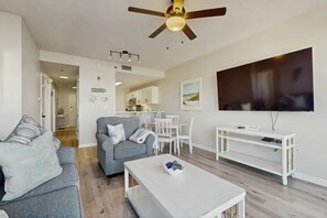 A living room with a sofa, coffee table, TV, and a ceiling fan. - 🎣 Palm Court Yacht Club 312B | Waterfront Views, Pool & Fishing Dock 🌊 (Fort Walton Beach)