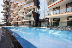 A modern hotel with a pool, multiple balconies, and a contemporary design. - Duplex 3BR with Garden Terrace & Glass Lounge (Dubai)