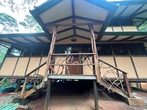 Ein Gebäude mit einer Holztreppe, die zu einem überdachten Eingang führt.