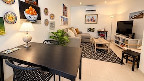 Una sala de estar moderna con una mesa de comedor, sofá y televisor.