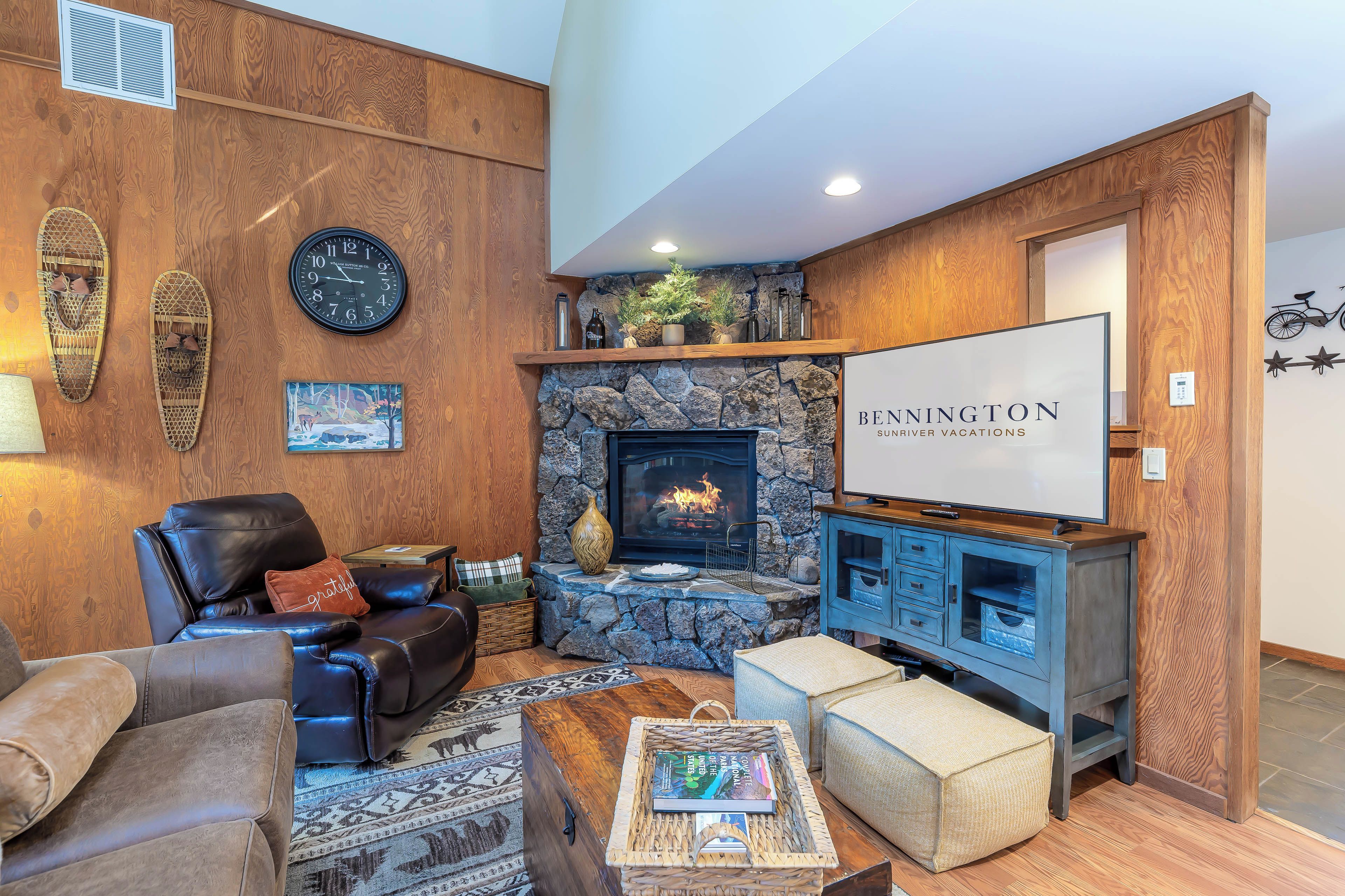 A cozy living room with a fireplace, leather furniture, and a sign for 'BENNINGTON SUNDRIVER VACATIONS'.