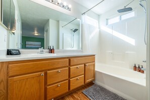 Ein modernes Badezimmer mit einem Holz-Waschtisch, einem großen Spiegel, einer Dusche und einer Badewanne.