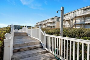 A wooden boardwalk leading to a beachfront property with white railings and multiple balconies. - Oceanfront 2BR Condo | Pool + Covered Deck + Easy Beach Access (Pine Knoll Shores)
