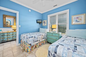 A bedroom with two beds, a dresser, a mirror, and a window with blinds. - Oceanfront 2BR Condo | Pool + Covered Deck + Easy Beach Access (Pine Knoll Shores)