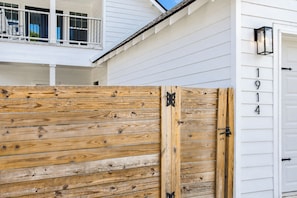 En träport med ett metallspänne, ett vitt hus med en balkong och en garageport med siffrorna ’1914’ synliga.