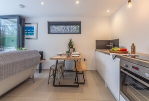 A compact kitchen with a dining table, a bench, and a small potted plant. - Garden Room, Westmeston, Sussex (Westmeston)