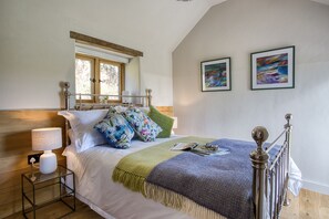 A bedroom with a bed, bedside table, lamp, and two framed artworks on the wall. - Little Barn, Minsterley, Shropshire (Minsterley)