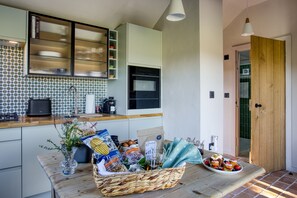 A kitchen with a tiled backsplash, a coffee maker, and a basket of groceries on the counter. - Little Barn, Minsterley, Shropshire (Minsterley)