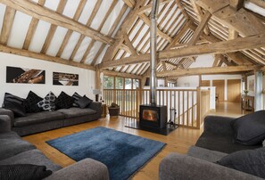A spacious living room with a high wooden ceiling, a fireplace, and a sofa with patterned cushions. - Wall Hills Barn, Bromyard, Herefordshire (Bromyard)