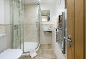 Ein Badezimmer mit Duschkabine, Toilette, Waschbecken und Handtuchhalter.