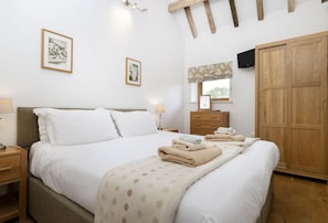 Ein Hotelzimmer mit Bett, Nachttisch, Kommode, Kleiderschrank und zwei gerahmten Bildern an der Wand.