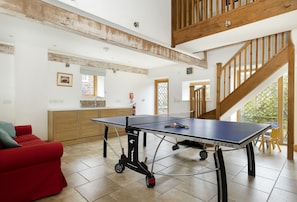 A spacious room with a ping pong table, a red sofa, and a staircase. - Wall Hills Barn, Bromyard, Herefordshire (Bromyard)