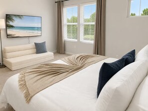 Une chambre à coucher avec un lit, un canapé, une télévision et une fenêtre avec des stores.