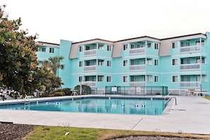 A turquoise multi-story building with balconies, a swimming pool, and a fenced area. - SeaSpray 305 | Oceanview Condo w/ Pool (Atlantic Beach)