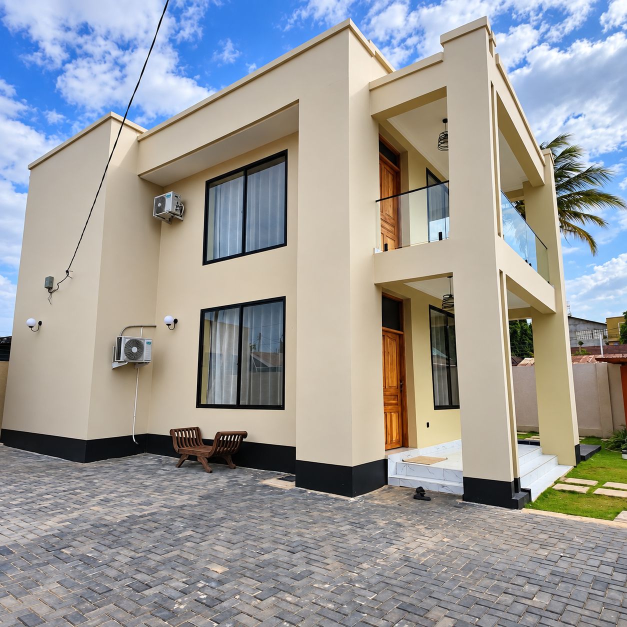 A modern two-story building with a flat roof, large windows, and a paved driveway.