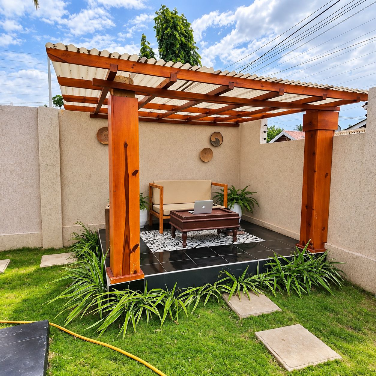 Ein überdachter Patio-Bereich mit einer Holz-Pergola, einer Couch, einem Couchtisch mit einem Laptop und topfgestellten Pflanzen.