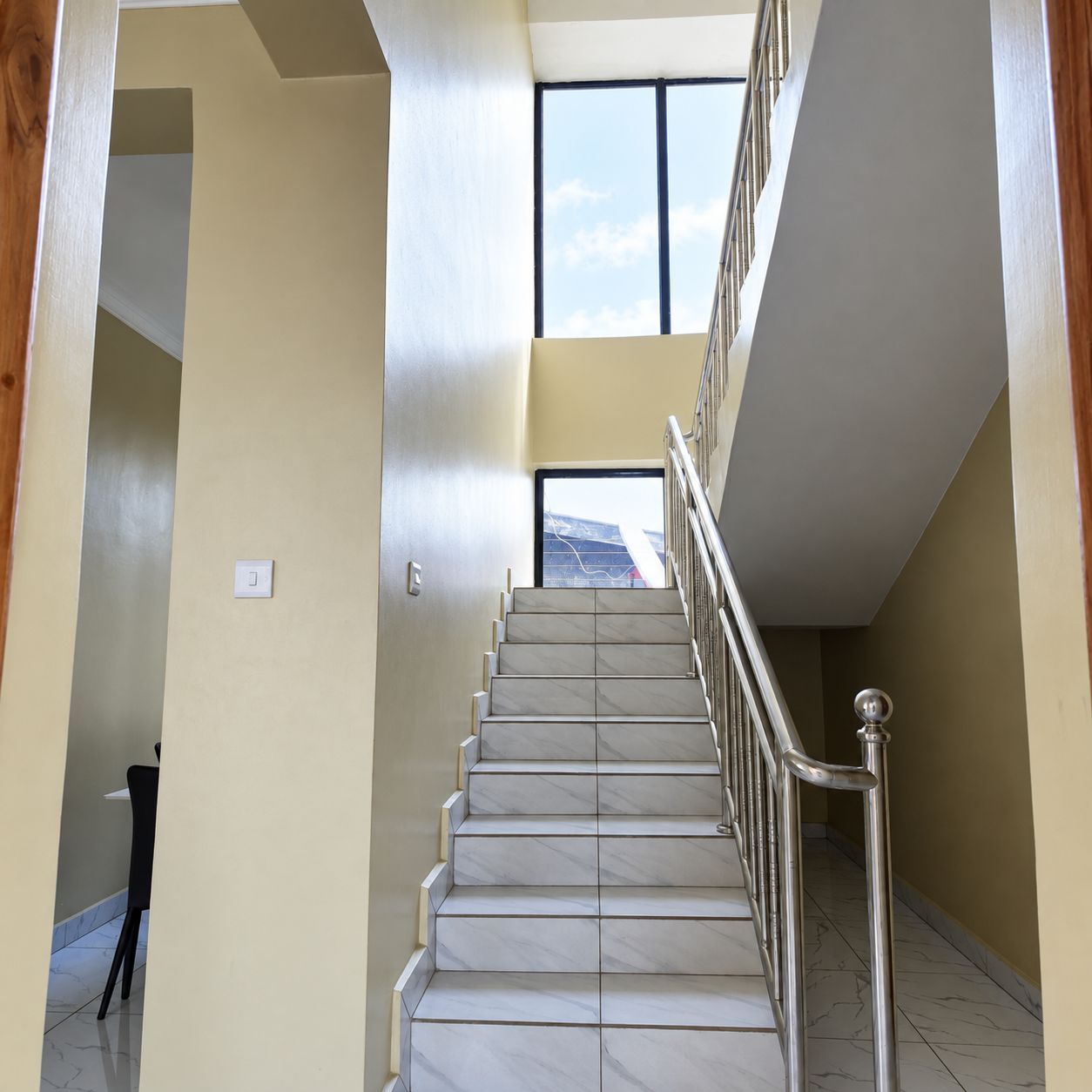 Un escalier avec une rampe métallique menant à un palier.