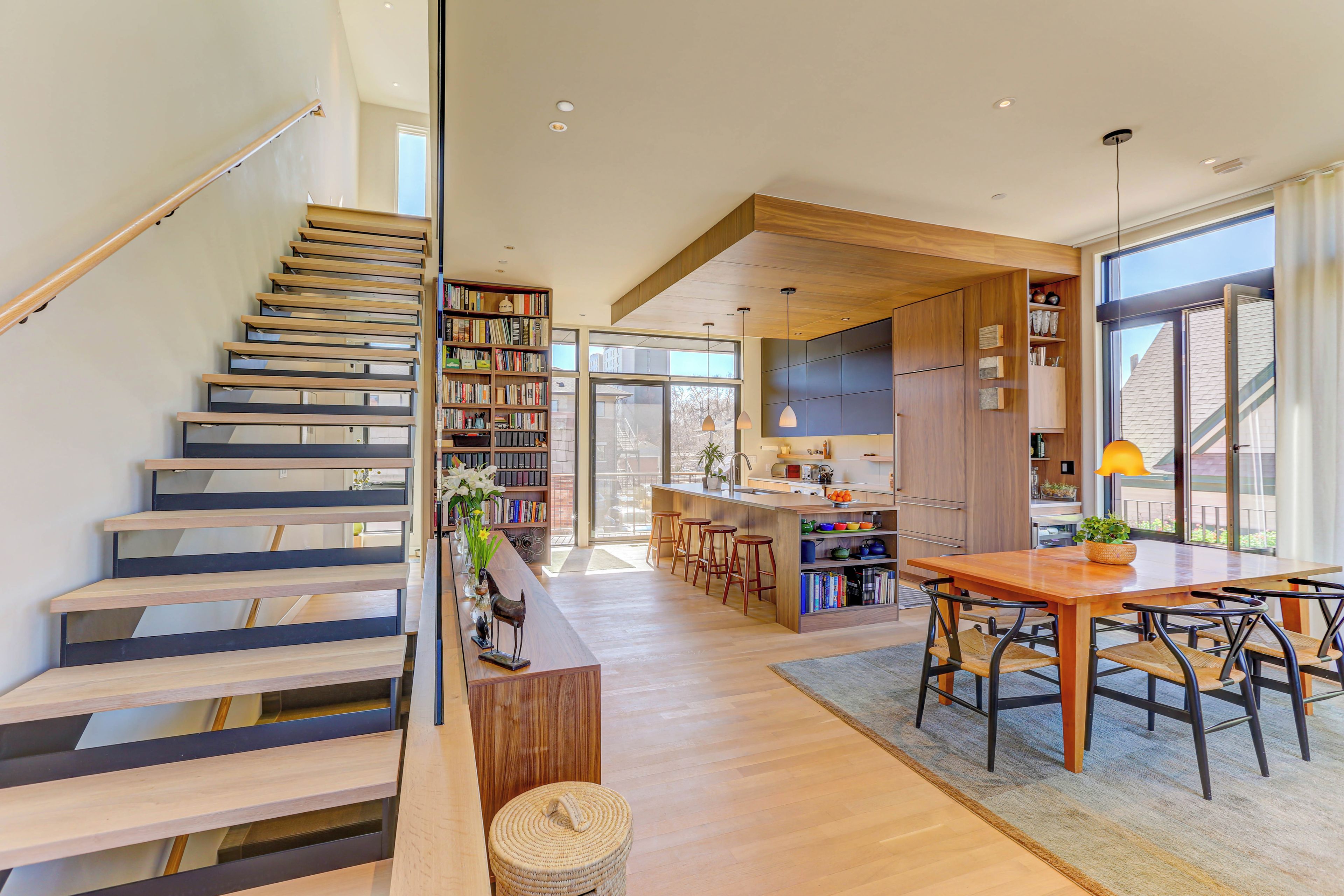 A modern interior with a staircase, a kitchen area, and a dining space.