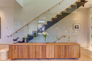 A modern interior with a wooden reception desk, a glass staircase, and a view of the outside. - L'Avenir on Oak | Steps from Old Town Square (Fort Collins)