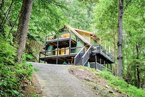 Uma cabana com estrutura em vários níveis, cercada por uma floresta densa.