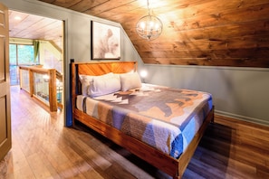 Quarto com cama de madeira, um candelabro e vista para uma varanda.