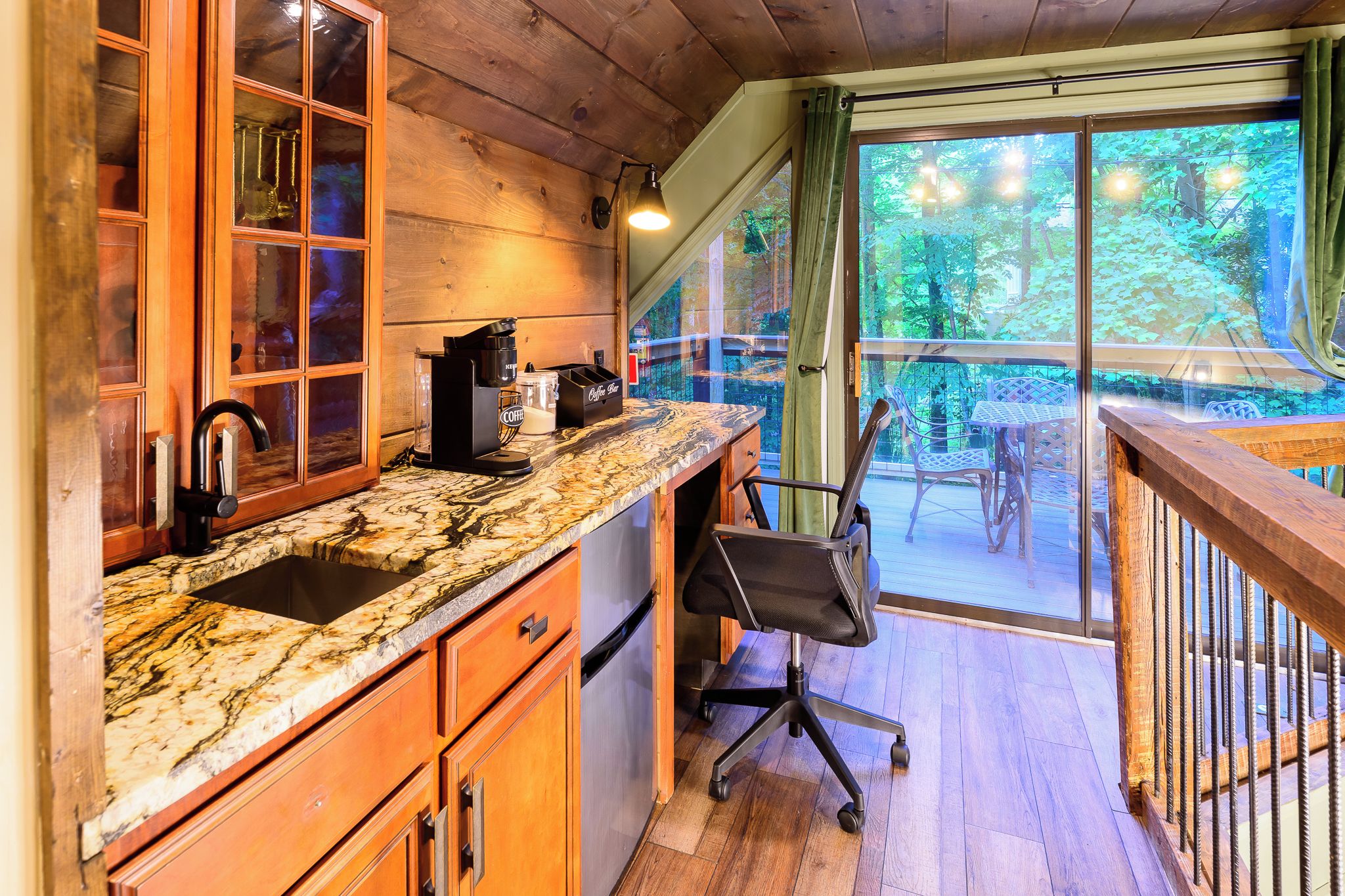 Una cocina con cafetera, un lavamanos y ventana con vista a una terraza.