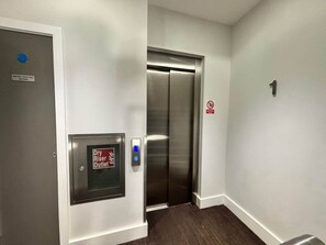 A hallway with a door labeled 'Dry Riser Outlet' and an elevator. - City Court - Stylish 1BR Home in the City (London)