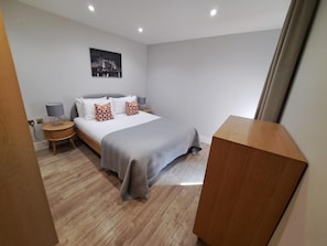 A hotel room with a bed, bedside tables, a lamp, and a picture on the wall. - City Court - Stylish 1BR Home in the City (London)