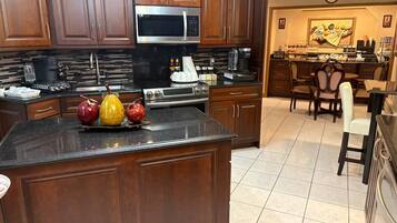 Una cocina con armarios de madera oscura, un microondas de acero inoxidable, una cafetera y un frutero sobre la encimera.