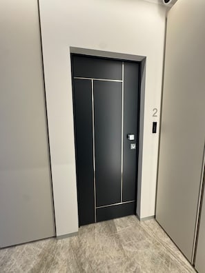 A modern elevator with a black door, a digital display, and a number '2' on the wall. - Giudecca 10 Guest House (Reggio Calabria)