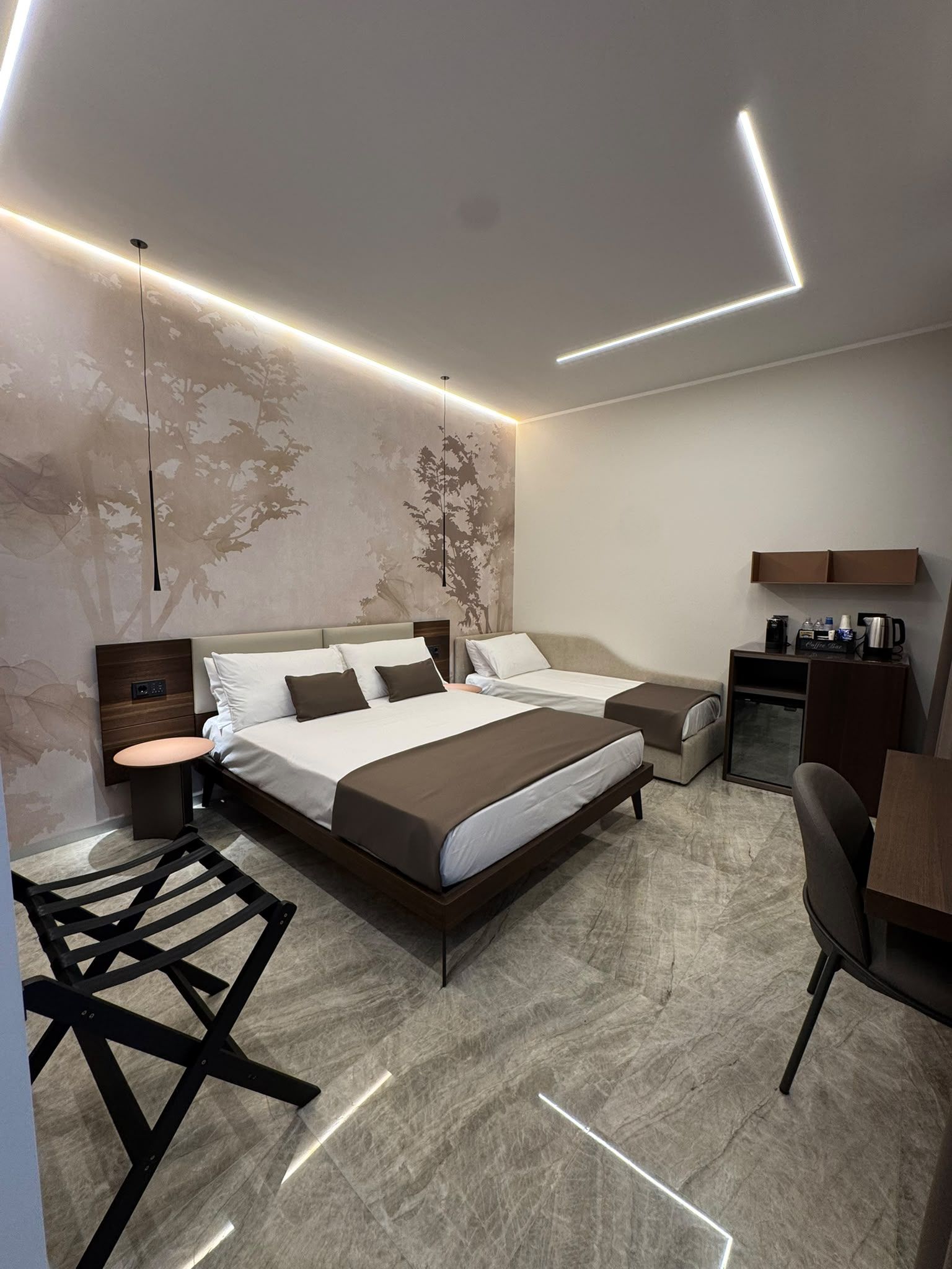 A modern hotel room with a large bed, bedside tables, a desk, and a chair.