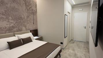 Ein modernes Schlafzimmer mit einem großen Bett, einem an der Wand befestigten Fernseher und einem Flur, der zu einer Tür führt.