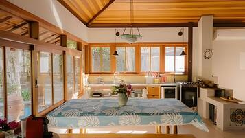 A modern kitchen with wooden beams, large windows, and a dining area with a table.